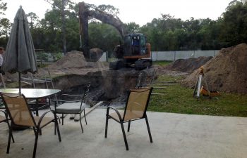 backyard swimming pool under construction - digging excavation with JCB machinery