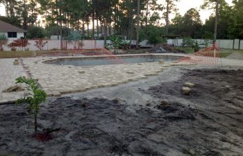 backyard swimming pool under construction - installing paver deck