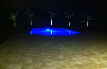 night view of a backyard swimming pool with blue light